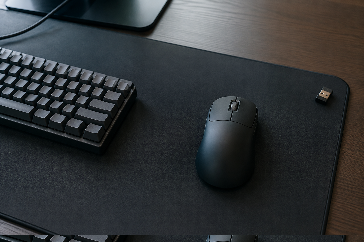 Black ultra-light wireless gaming mouse on a large mousepad beside a keyboard